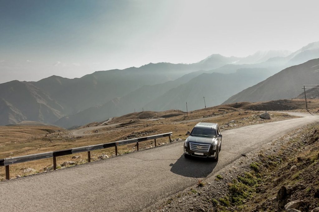 A scenic drive through Almatys mountain ranges with a parked SUV during the day.