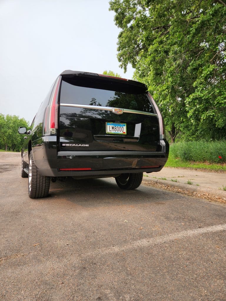 Rear view of CMB Transport’s black Cadillac Escalade, highlighting luxury SUV styling and professional black car service for VIP clients across Minnesota.