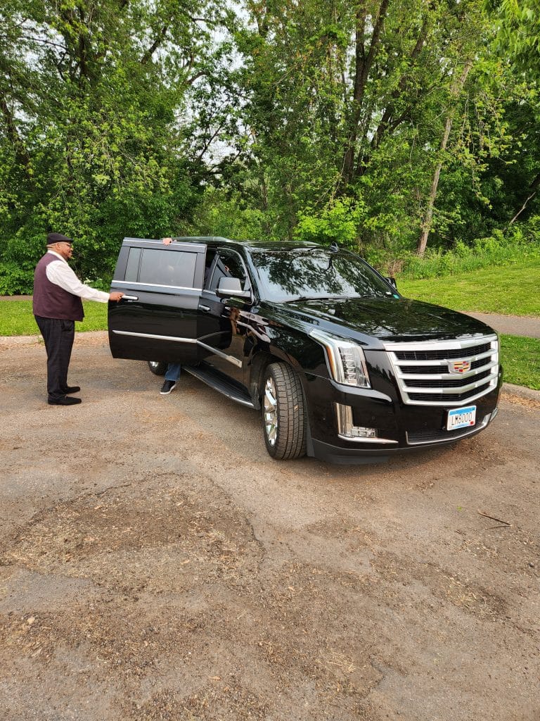Luxury transportation by CMB Transport as chauffeur Chris assists a corporate VIP showcasing executive black SUV service with top-tier professionalism and comfort