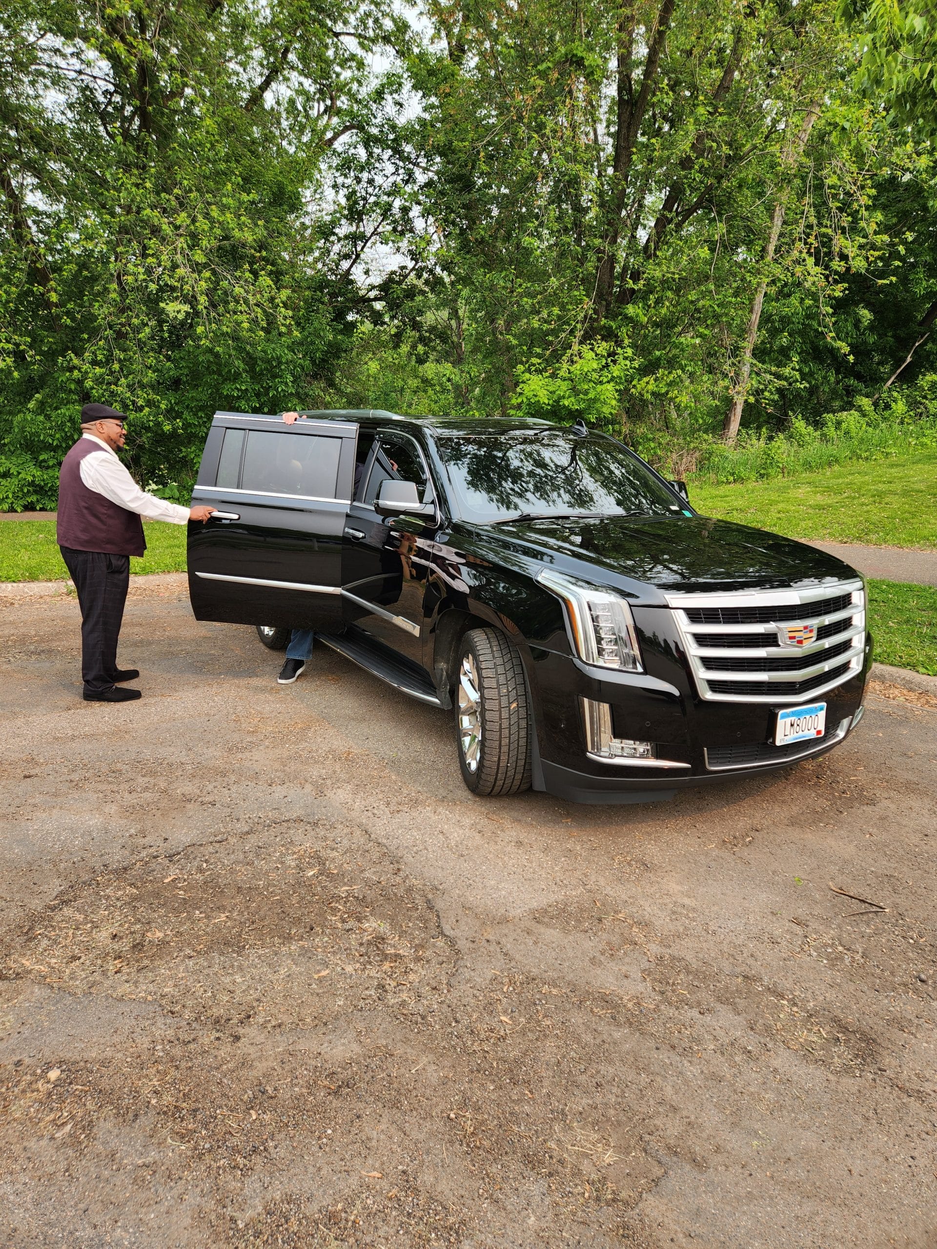 Luxury transportation by CMB Transport as chauffeur Chris assists a corporate VIP showcasing executive black SUV service with top-tier professionalism and comfort