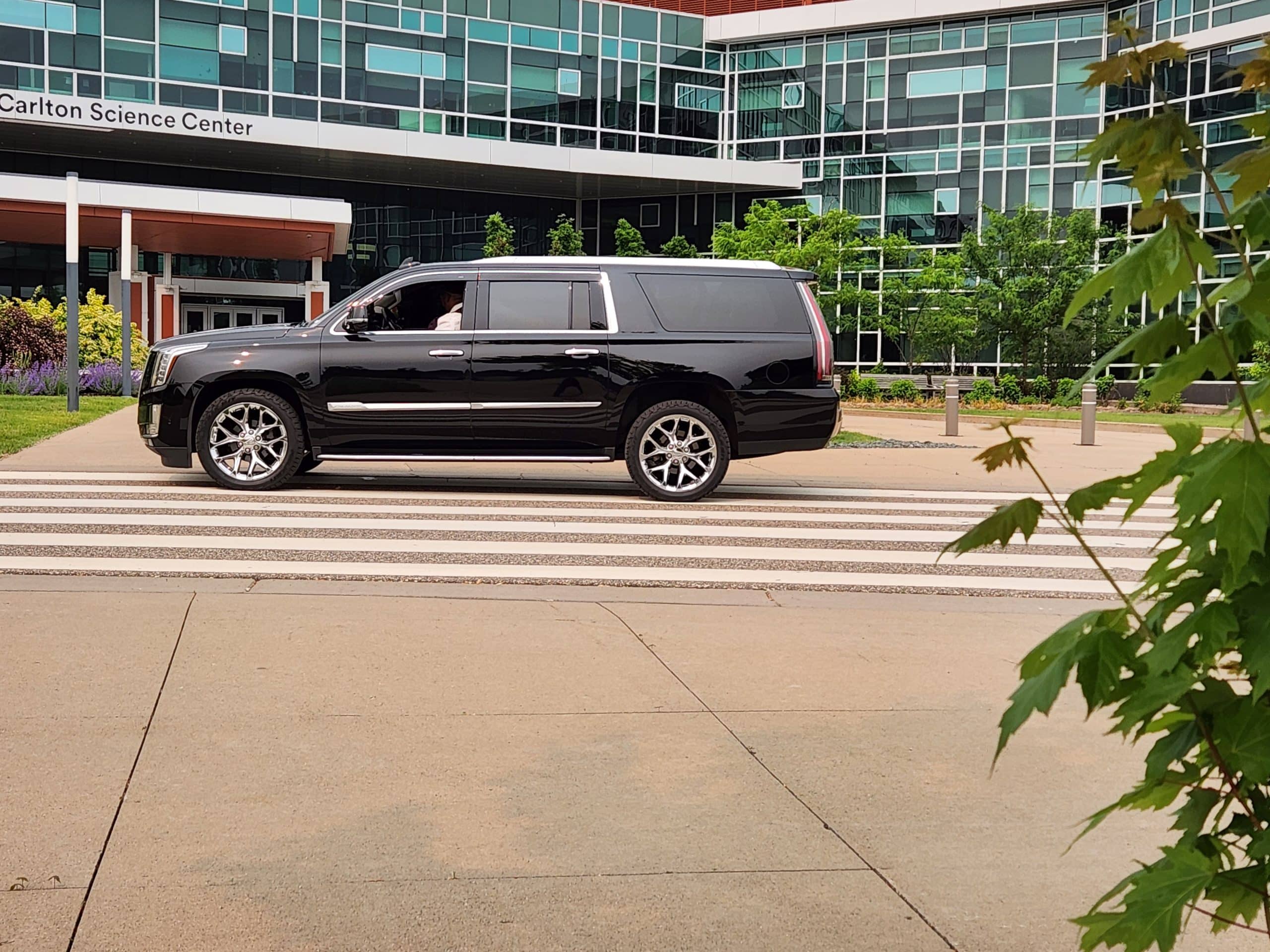 CMB Transport’s luxury Cadillac Escalade positioned in front of a modern business complex, perfect for corporate chauffeur services in Minneapolis and Twin Cities.