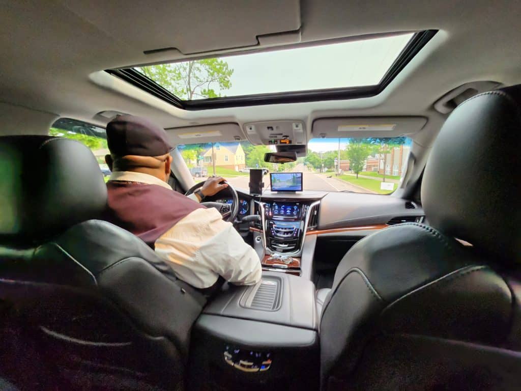 Back seat perspective of Cadillac Escalade with CMB Transport driver, offering smooth, professional chauffeur service and first-class passenger experience.
