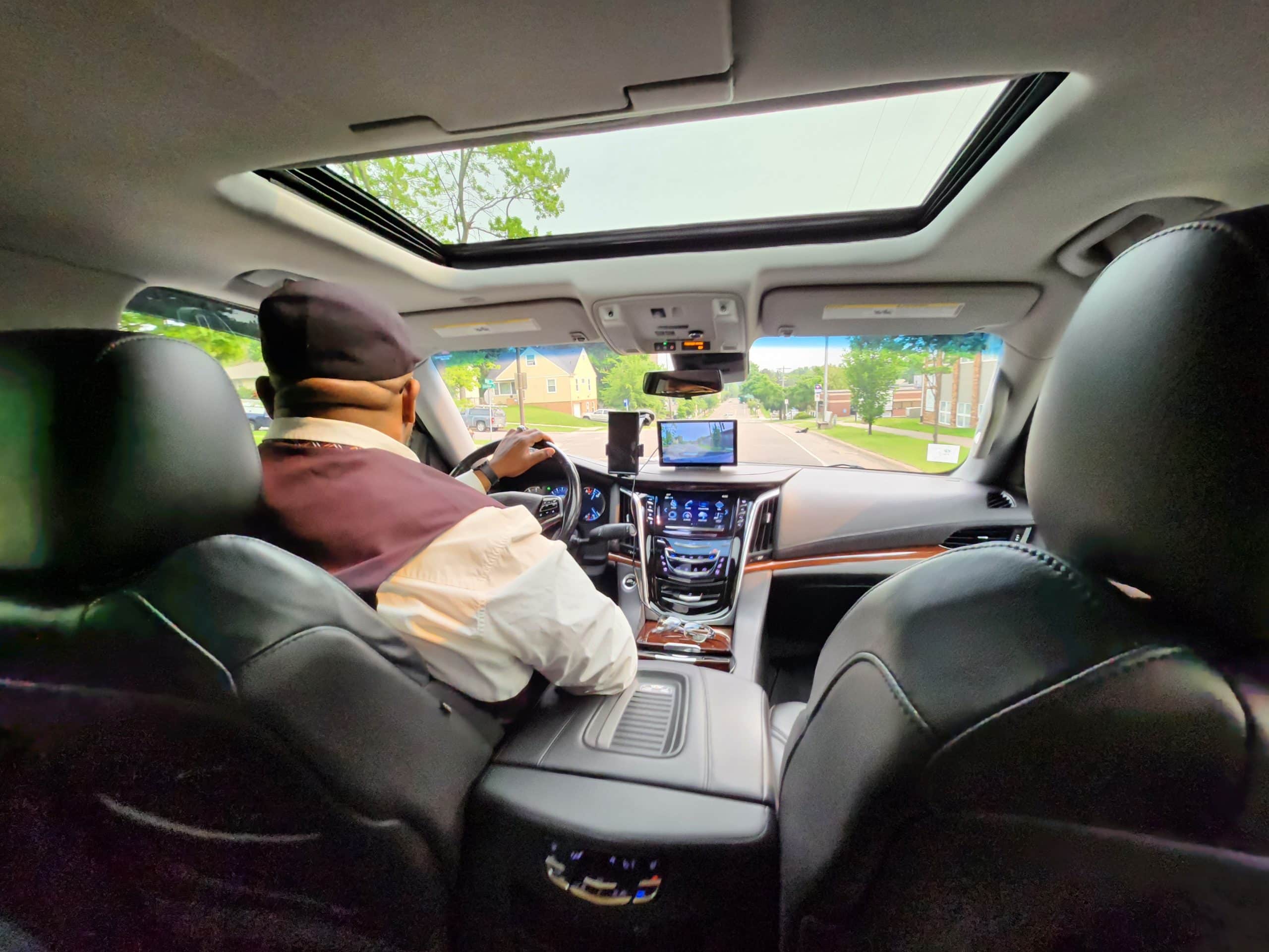 Back seat perspective of Cadillac Escalade with CMB Transport driver, offering smooth, professional chauffeur service and first-class passenger experience.