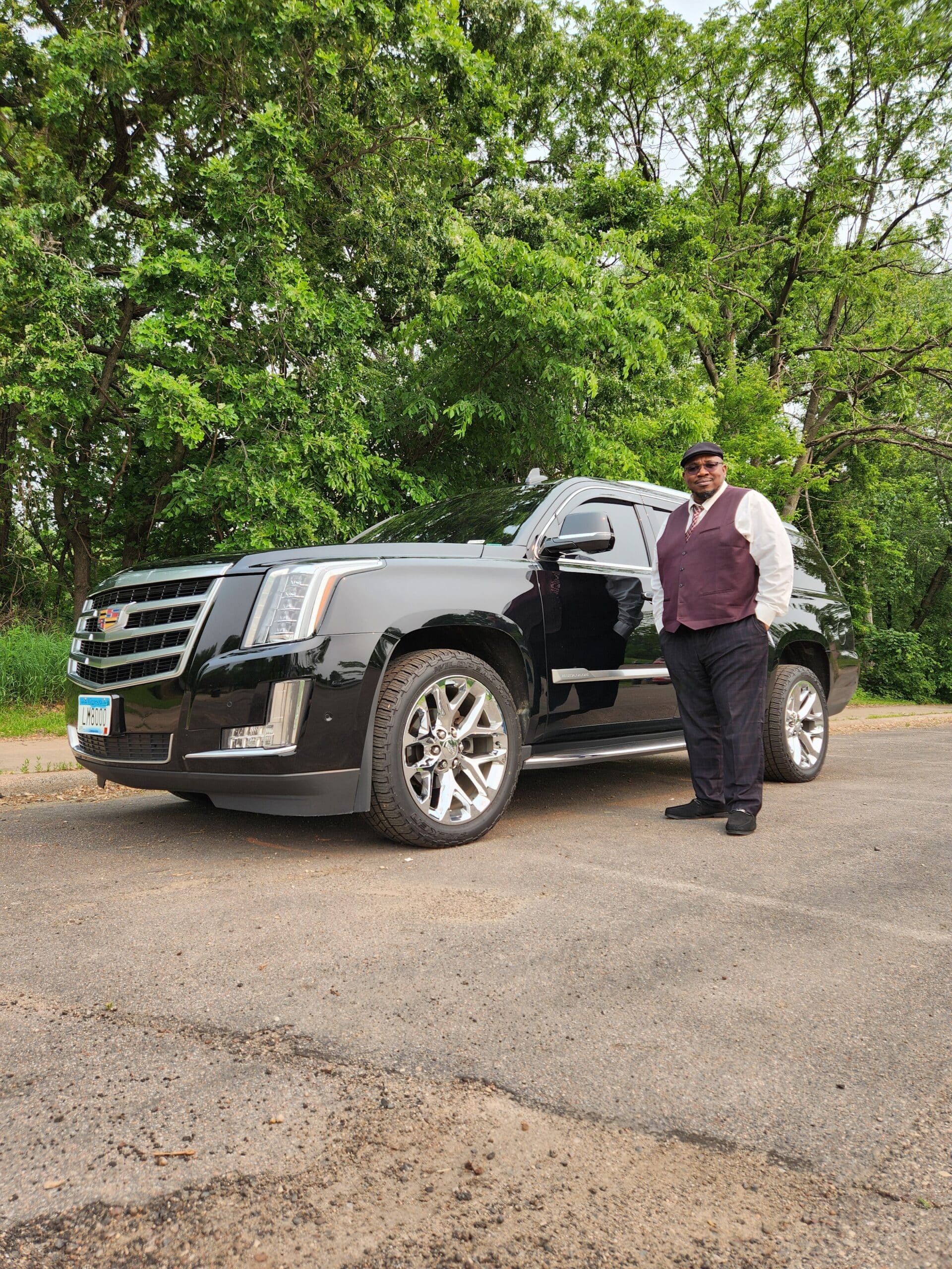 Luxury chauffeur service featuring a suited driver with a black Cadillac Escalade, ideal for executive travel, airport transfers, and upscale event transportation.