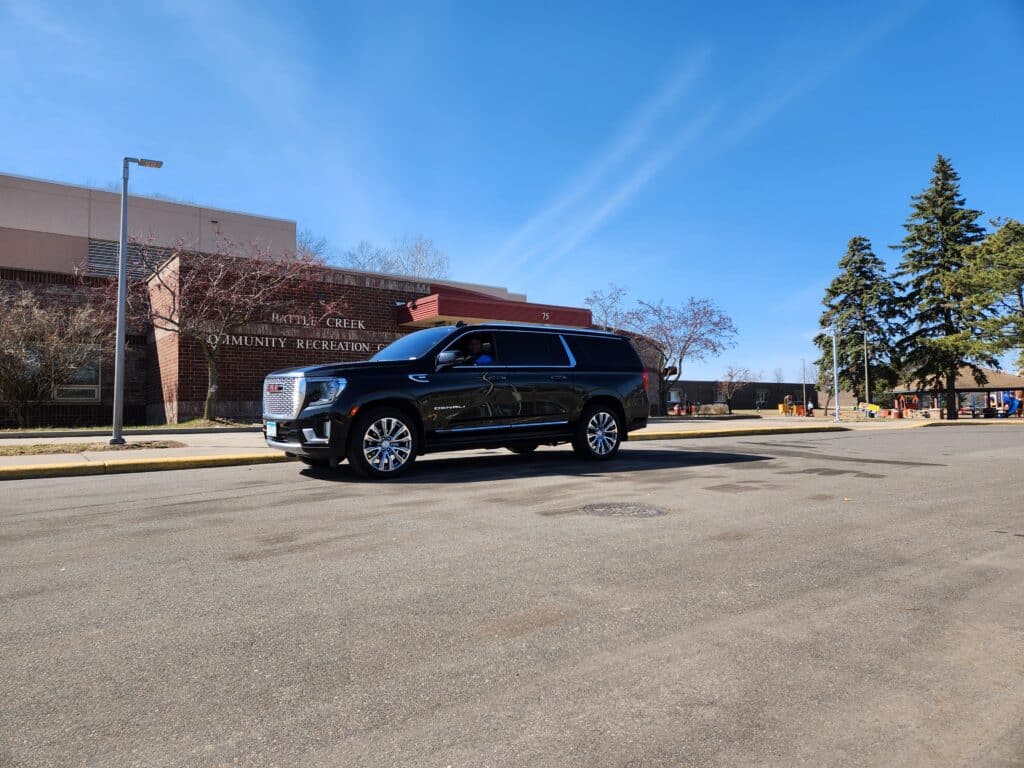 Black CMB Transport vehicle parked in front of downtown Minneapolis skyline at dusk